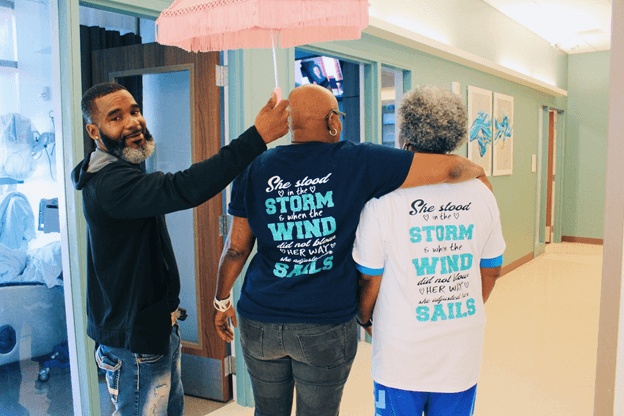 Man holding a pink umbrella over patient